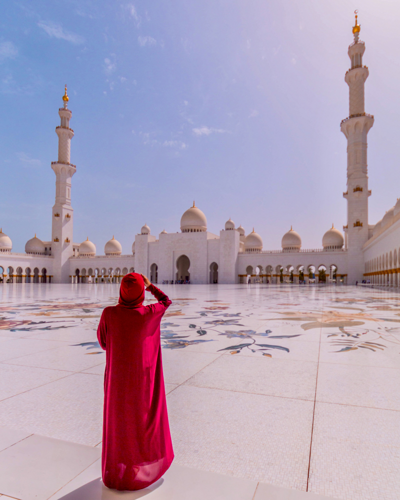 A girl in Abaya looking at the architecture of Grand mosque from the corridor