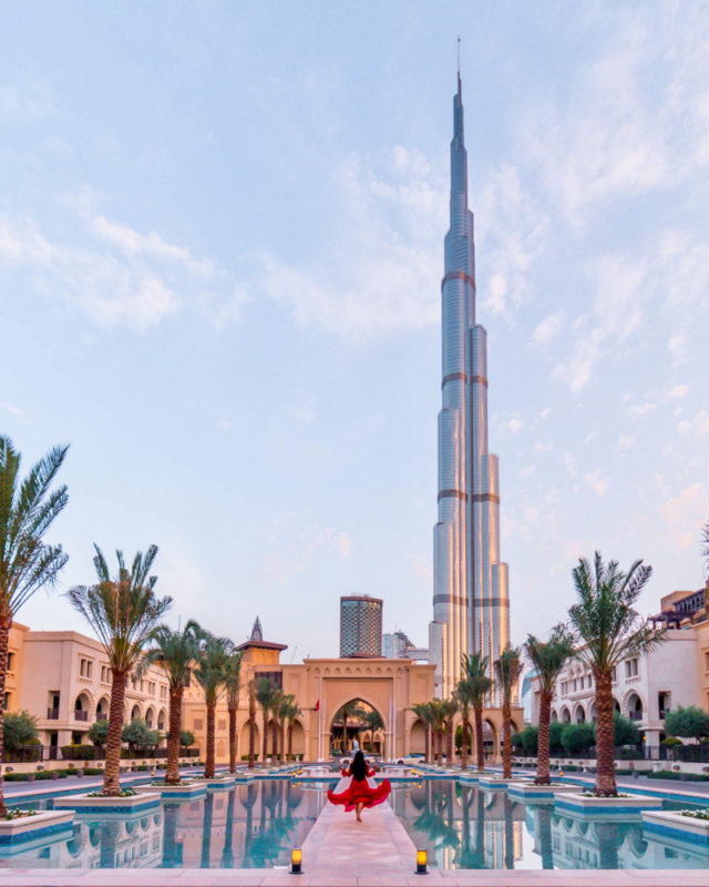 A girl in red dress posing in front of Palace downtown with a view of Burj Khalifa in Dubai