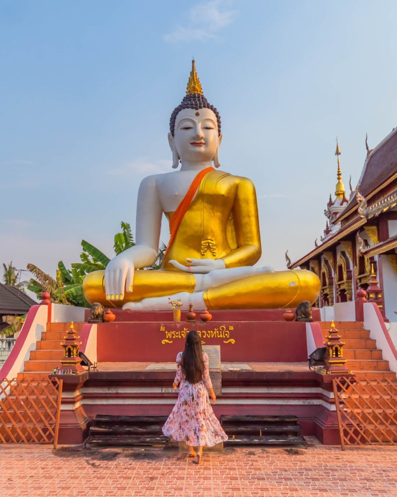 A girl standing in front of Buddha statue at Wat Rajamontean temple in Chiang Mai