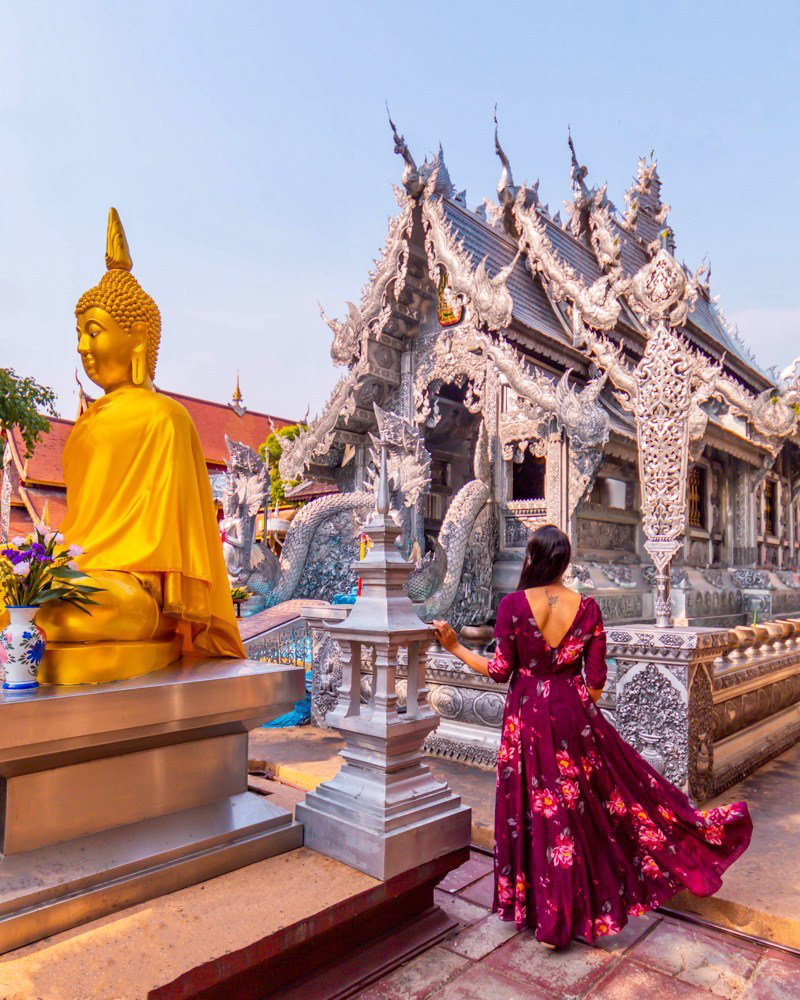 A girl in burgundy dress standing in front of silver temple in chiang mai