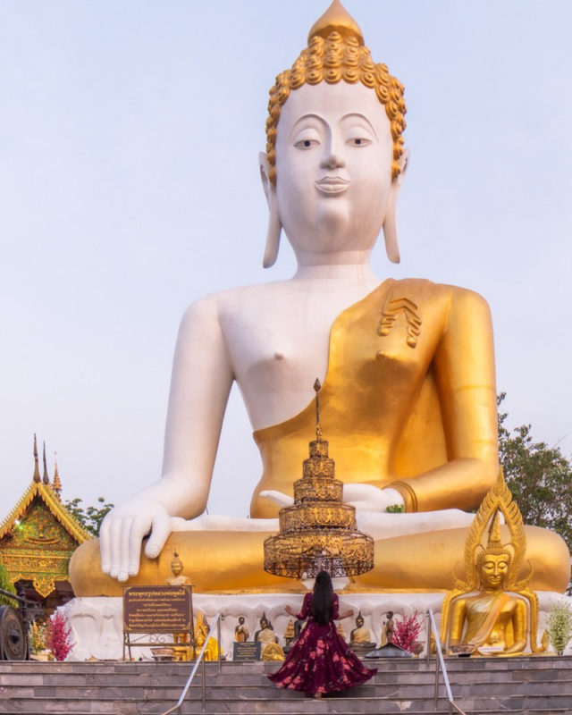 A girl in a dress standing in front of big Buddha Statue in Chiang Mai