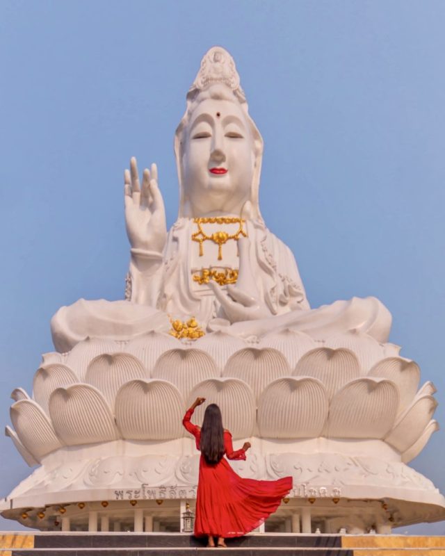 A girl in red dress standing in front of Big buddha