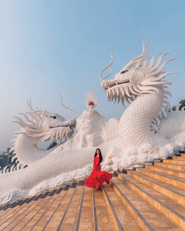 A girl in red dress standing in front of dragon statues