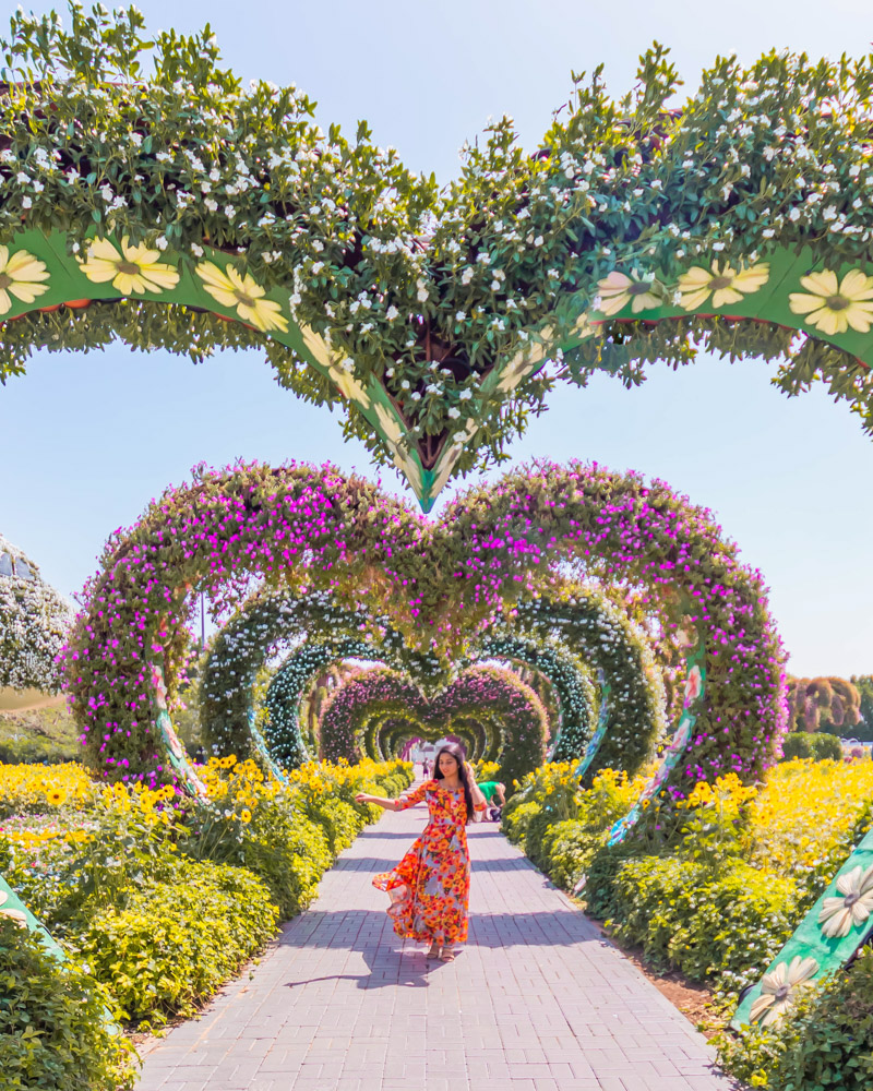 A girl posing amongst the flower arches in miracle garden