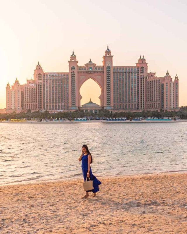 A girl in blue dress standing at the beach at Pointe with a view of Atlantis the palm in Dubai