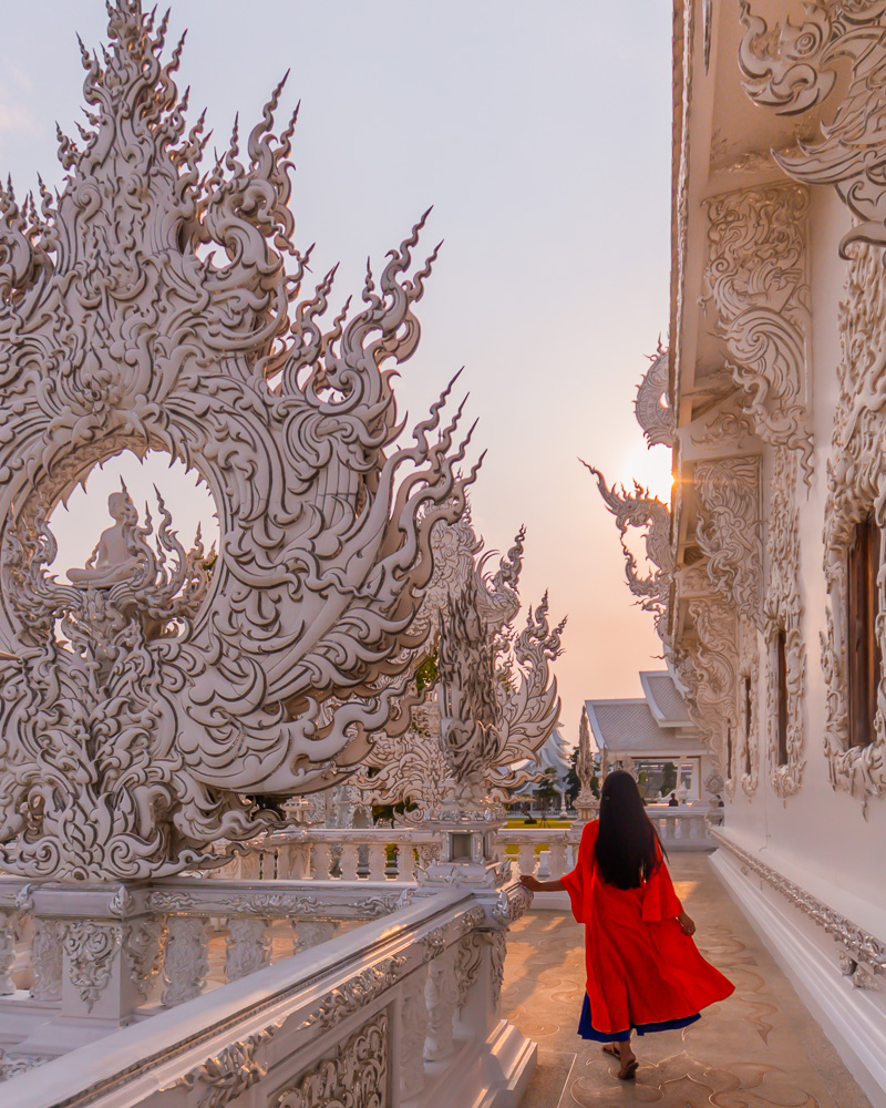 A girl in orange cape standing at the side of main building at white temple