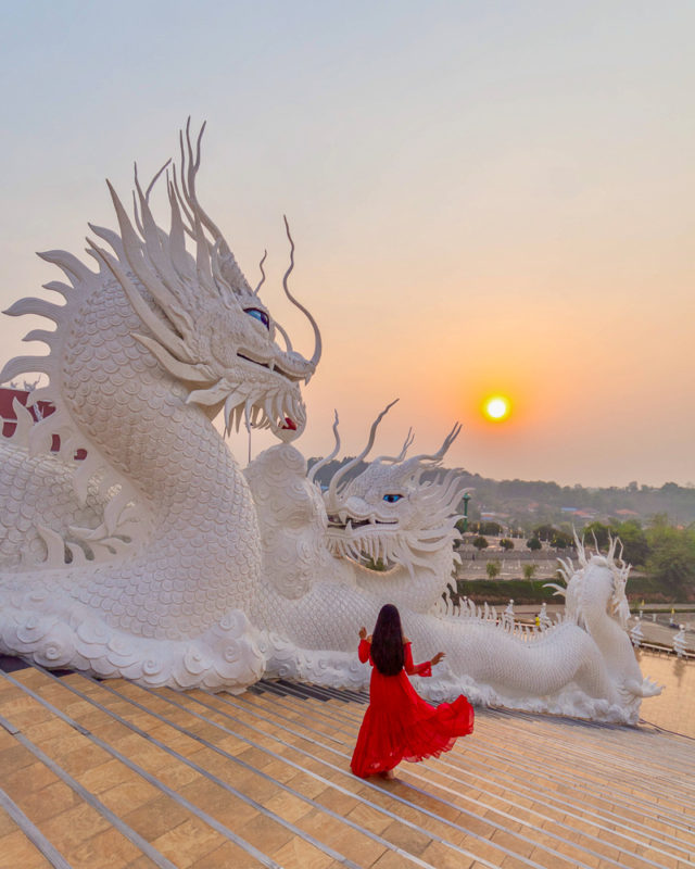 A girl in red dress amongst dragon statues