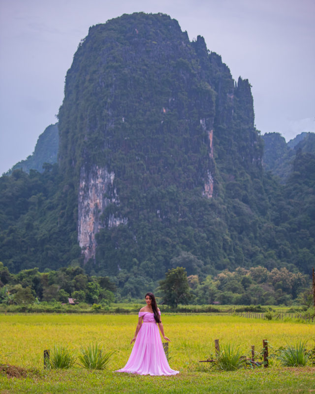 A girl in pink dress standing in rice paddies in vang vieng