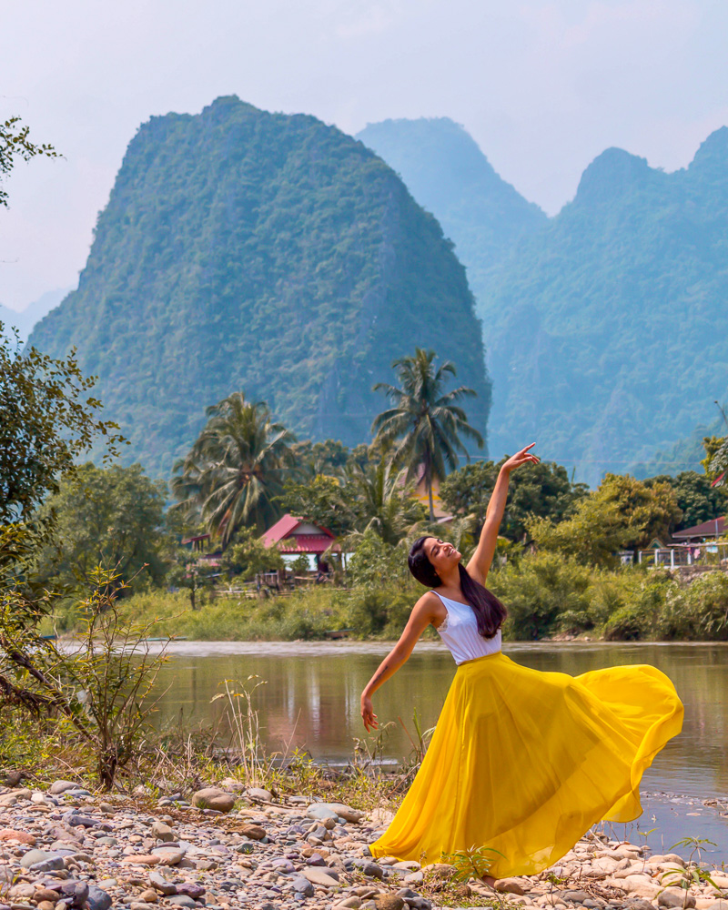 A girl in yellow skirt dancing in front of mountains