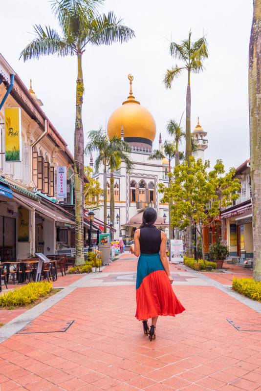 A girl in orange skirt posing in front of MASJID SULTAN MOSQUE in singapore